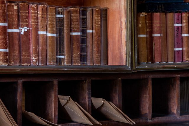 Libri antichi rilegati, allineati su uno scaffale di legno